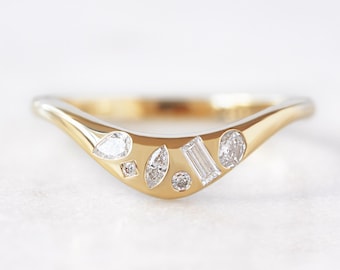 May include: A gold and white curved band ring with a cluster of small diamonds set in the center.