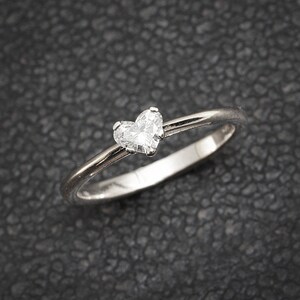 Könnte beinhalten: Ein silberner Ring mit einem herzförmigen Diamanten.