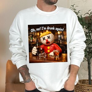 Könnte beinhalten: Weißes Sweatshirt mit einer Cartoonfigur mit gelbem Hut und roter Jacke, die eine Bierflasche und einen Schnaps hält. Der Text "Oh, no! I'm drunk again!" ist über der Figur zu sehen.