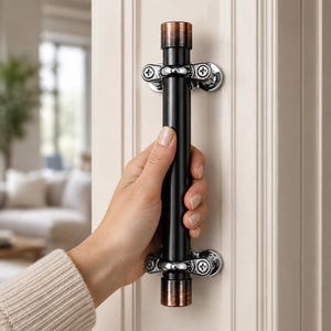 May include: A vertical door handle featuring a long black cylindrical center, polished chrome mounting brackets with visible screws, and copper-toned metallic caps at both the top and bottom ends, attached to a white paneled door surface.