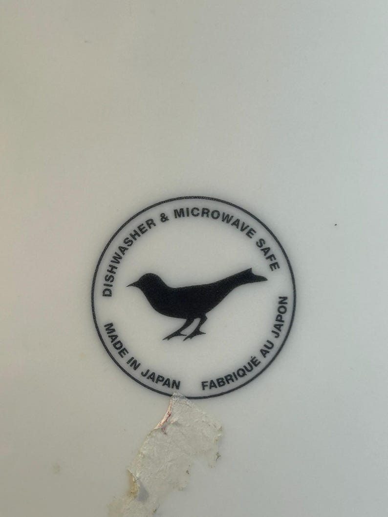Peut inclure: Surface blanche avec un graphisme circulaire noir. Le graphisme pr&eacute;sente une silhouette d'oiseau et le texte "Dishwasher & Microwave Safe", "Made in Japan" et "Fabriqu&eacute; au Japon".