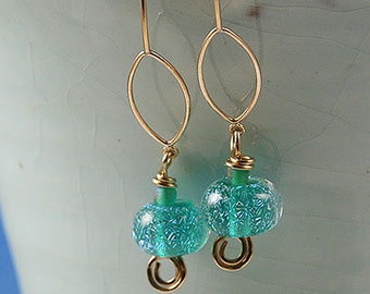 Flame worked lentil shape bead with 23.4 kt gold foil and black stringers in scroll design