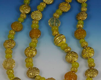 Flame worked lentil shape bead with 23.4 kt gold foil and black stringers in scroll design