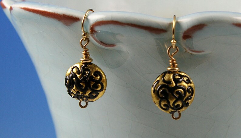 Flame worked lentil shape bead with 23.4 kt gold foil and black stringers in scroll design
