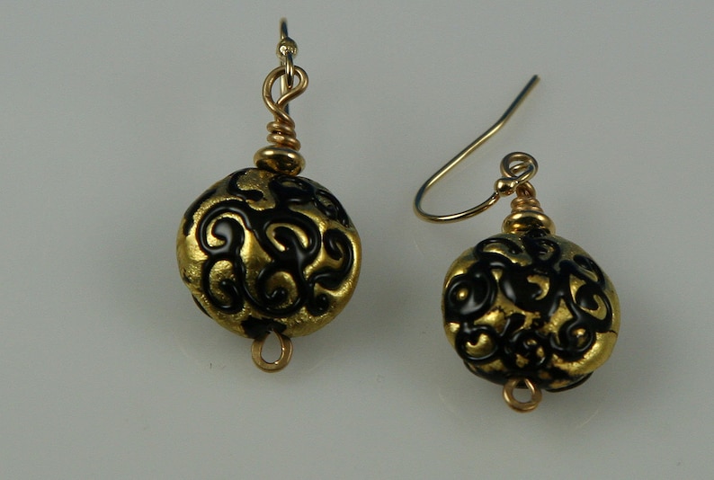 Flame worked lentil shape bead with 23.4 kt gold foil and black stringers in scroll design