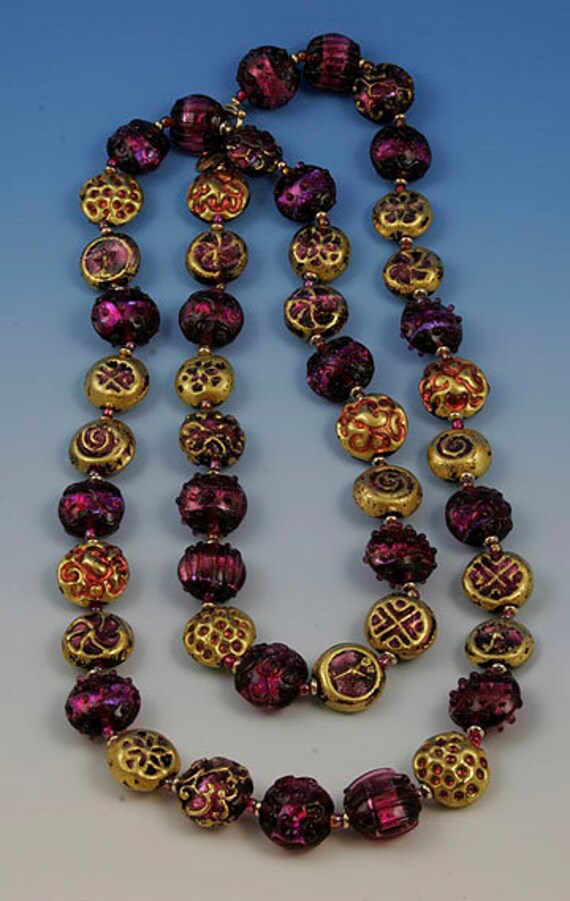 Flame worked lentil shape bead with 23.4 kt gold foil and black stringers in scroll design