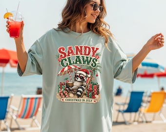 Camiseta navideña de Sandy Claws en julio, camiseta divertida de vacaciones en la playa con mapache