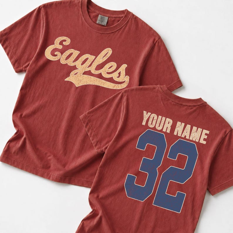two red t-shirts with the word "Eagles" printed on them, and the back of one t-shirt has the text "YOUR NAME" and the number "32" printed on it.