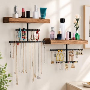 May include: Two wall-mounted jewelry organizers with wooden shelves and black metal racks. The shelves hold cosmetics, while the racks display necklaces, bracelets, and earrings. The jewelry includes gold and silver necklaces, and colorful beaded bracelets.