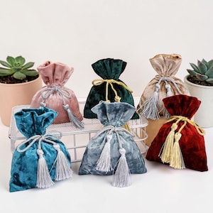 May include: A collection of velvet drawstring bags in various colors, including teal, pink, green, beige, gray, and red. Each bag is tied with a matching or contrasting cord and tassel, perfect for small gifts or storage.