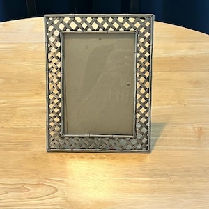 May include: A rectangular picture frame with a metallic silver finish. The frame features a woven lattice pattern throughout the border, framed by a bamboo-style outer edge. The center contains a plain, light-colored insert behind a clear pane.