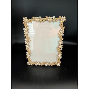 May include: A rectangular picture frame featuring a gold-toned metal border with a textured, vine-like pattern. The frame is embellished with numerous small, white, round faux pearls and clear, sparkling crystals arranged in floral clusters.