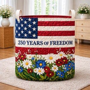 May include: A round storage basket with a patriotic design. The top half features the American flag, with the text "250 YEARS OF FREEDOM" below. The bottom half is decorated with colorful flowers.