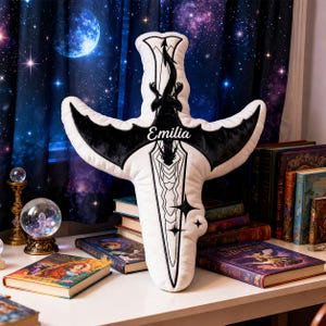 May include: A white plush sword-shaped pillow with black accents, including a dragon silhouette and the name "Emilia". The pillow has a cross-shaped design with star details. The background includes books and a starry night curtain.