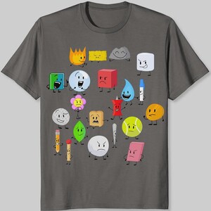 May include: Dark gray t-shirt featuring a colorful graphic of cartoon characters. The design includes various shapes and objects with expressive faces, such as a flame, a cube, a tennis ball, and a pencil. The shirt is made of a soft material.