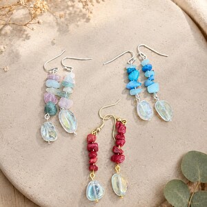 May include: Three pairs of dangle earrings featuring irregular chip-style gemstones in pink, green, blue, and red, each finished with a single iridescent, translucent, oval-shaped bead suspended from silver-tone or gold-tone metal hooks.
