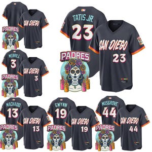 Op de afbeelding: Een verzameling marineblauwe honkbalshirts van de San Diego Padres. Elk shirt heeft spelersnamen en -nummers, met oranje en witte accenten. De shirts worden getoond met een Dia de los Muertos-thema Padres logo.