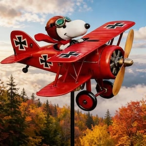 May include: A red biplane with a cartoon dog character wearing a pilot's helmet and goggles. The plane has black crosses on the wings and a wooden propeller. The background shows a colorful autumn landscape.