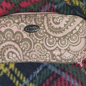 Puede incluir: Un estuche rectangular con cremallera y un estampado de cachemira rosa y marrón. El estuche tiene un emblema plateado y un tirador de cremallera verde. El estuche mide aproximadamente 20 cm de largo.