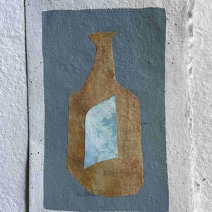 Peut inclure: Œuvre d'art abstraite représentant une forme de bouteille marron avec un accent bleu clair, sur un fond bleu clair. L'œuvre est sur du papier blanc cassé texturé avec un bord dentelé, créant une esthétique artisanale.