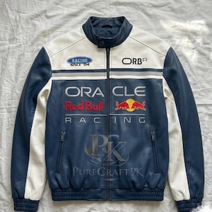 May include: A blue, white, and black leather jacket with a zip-up front. The jacket features the text "RACING SINCE '04", "ORBR", "ORACLE", and "Red Bull Racing". It has two front pockets and a stand-up collar.