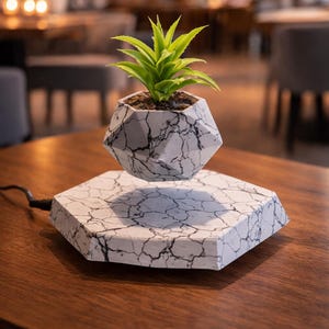 May include: A white ceramic mug with a black handle and the text "But First, Coffee" in a black, bold font. The mug is on a white surface.