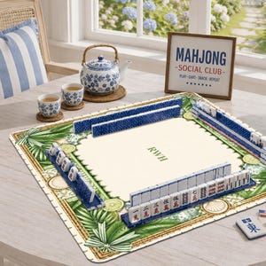 K&ouml;nnte beinhalten: Eine quadratische Mahjong-Matte mit cremefarbenem Zentrum und den Initialen RWH, umgeben von einem gr&uuml;nen botanischen Rand mit Limettenscheiben und Muscheln. Blaue Mahjong-Steine sind auf der Matte angeordnet. Ein Schild tr&auml;gt die Aufschrift MAHJONG SOCIAL CLUB.