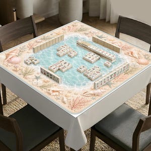 Op de afbeelding: Een vierkant mahjong-tafelkleed met een strandthema, voorzien van lichtblauw water, wit zand, schelpen en koraal. Op het oppervlak liggen ivoorkleurige mahjong-tegels met diverse zwarte en rode Chinese karakters en symbolen afgebeeld.