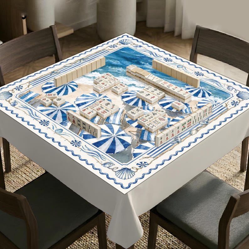 May include: A square table cover featuring a beach scene with blue and white striped umbrellas, seashells, and ocean waves. The surface is printed with a mahjong game layout, including multiple sets of ivory-colored mahjong tiles arranged in rows.