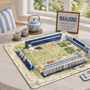 May include: A mahjong set featuring blue and white tiles arranged on a green mat with a tennis-themed illustration of dogs. A blue and white floral teapot and two matching cups sit nearby, alongside a sign reading MAHJONG SOCIAL CLUB.