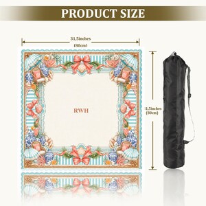 May include: A square mat with a light blue and white striped border, decorated with illustrations of chairs, umbrellas, bows, and shells. The center features the text RWH. It measures 31.5 inches by 31.5 inches and includes a black carrying bag.