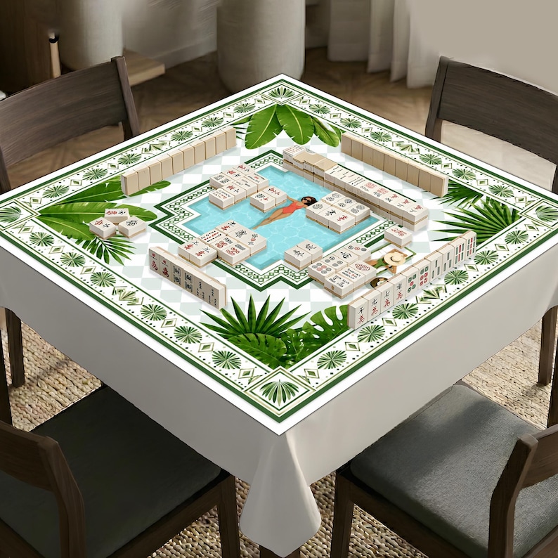 May include: A square mahjong table cover featuring a central swimming pool graphic with a person in a red swimsuit, surrounded by green tropical palm leaves and a white border. The surface is arranged with multiple ivory-colored mahjong tiles.