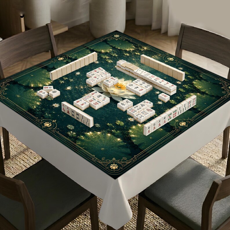 May include: A square mahjong mat featuring a dark green background with a central white lotus flower and gold decorative borders. The mat is covered with white mahjong tiles arranged in various groupings, including long rows and small stacks.