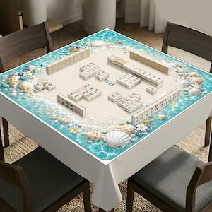Puede incluir: Un mantel cuadrado con dise&ntilde;o de playa, agua turquesa, arena blanca, conchas y estrellas de mar. El centro muestra un juego de Mahjong con fichas dispuestas sobre la superficie, incluyendo las letras WH impresas en el medio.