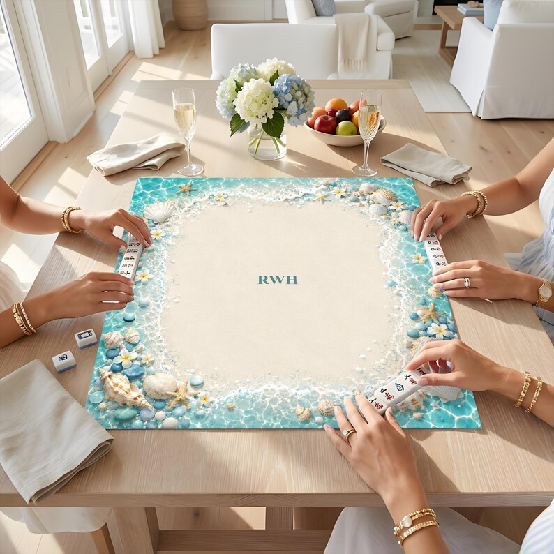 Puede incluir: Un tapete de mahjong cuadrado con dise&ntilde;o de playa que incluye agua turquesa, arena blanca, conchas, estrellas de mar y flores de plumeria. El centro muestra las letras RWH en un tono verde azulado oscuro, rodeado por un borde de olas.