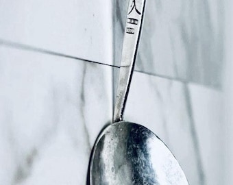 Cuchara antigua de Hanau, firmada M.E.K., plata 800, con figura de descanso, para crema o mermelada.