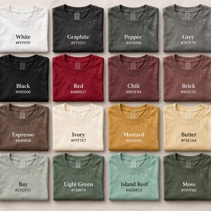 May include: Sixteen t-shirts in a range of colours, including white, black, and red. Each shirt is laid flat, with the colour name and hex code printed above. The colours vary from light to dark, with names such as "Graphite" and "Mustard".