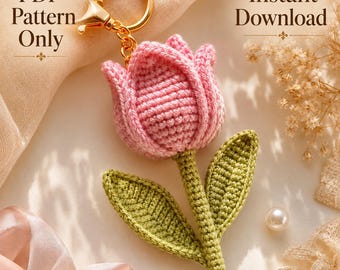 Peut inclure: Un porte-clés tulipe au crochet avec une fleur rose et une tige verte avec deux feuilles, fixé à un anneau en métal doré. L'image contient le texte PDF Pattern Only et Instant Download dans une police de caractères décorative.