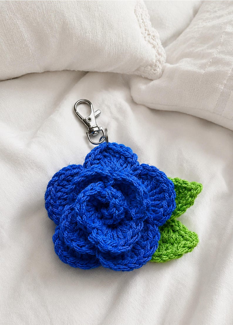 Peut inclure: Un porte-cl&eacute;s fleur en crochet compos&eacute; d'une fleur bleue aux p&eacute;tales superpos&eacute;s et de deux feuilles vert vif fix&eacute;es &agrave; la base. Le motif floral est reli&eacute; &agrave; un mousqueton en m&eacute;tal argent&eacute; pour une fixation facile sur des sacs ou des cl&eacute;s.