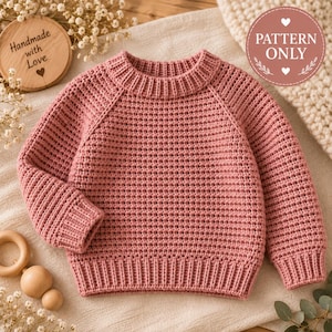 May include: A dusty rose long-sleeve sweater featuring a textured waffle knit pattern, a ribbed crew neckline, and ribbed cuffs and hem. The image includes a circular wooden tag with the text Handmade with Love and a circular badge with the text PATTERN ONLY.