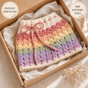 Puede incluir: Una falda de ganchillo con rayas horizontales en rosa pastel, amarillo, verde y morado, con una cintura acanalada de color crema y un cordón a juego. El texto INSTANT DOWNLOAD y PDF PATTERN ONLY aparece en insignias circulares.