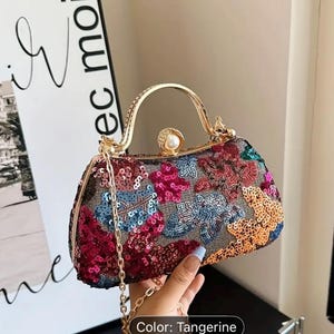 May include: A sequined handbag in various colours, with a gold handle and chain strap. The bag is decorated with pink, blue, and orange sequins. The text "Color: Tangerine" is visible.