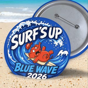 May include: A round pinback button featuring a cartoon red elephant on a surfboard riding a large blue ocean wave. The text reads SURF'S UP, BLUE WAVE, and 2026. A small red cap with the text MAGA is floating above the elephant's head.