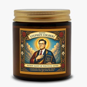 May include: A brown glass candle jar with a gold metal lid. The label features an illustration of Stephen Colbert as a saint, with the text: SAINT STEPHEN COLBERT, TRUTH OVER POWER, PATRON SAINT OF POLITICAL SATIRE, CANCELLED FOR TELLING THE TRUTH.