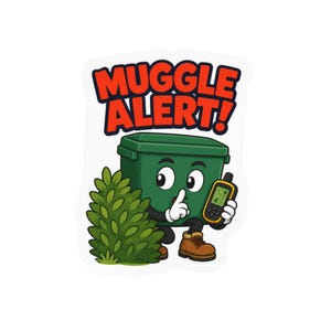 May include: A die-cut sticker featuring a green trash bin character hiding behind a green bush. The character holds a GPS device and makes a shushing gesture. Above the character, the text MUGGLE ALERT! is printed in bold red letters with a dark outline.