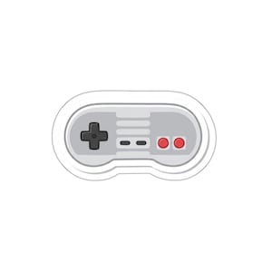 May include: A gray and white sticker of a classic video game controller. The controller has a black directional pad, two red buttons, and a series of small gray buttons. The controller is outlined in white.