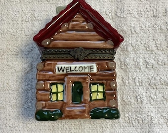 Caja de baratijas rústica de cerámica vintage con forma de cabaña, con bisagras y un alce en su interior.