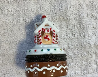 Caja de baratijas navideña con forma de casa de jengibre y un muñeco de jengibre detallado en su interior.