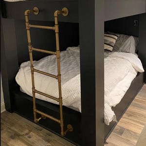 May include: A black bunk bed frame featuring a metallic gold pipe ladder attached to the side. The bed includes a white quilted comforter and a striped pillow. The structure is built with thick black posts and horizontal rails for support.