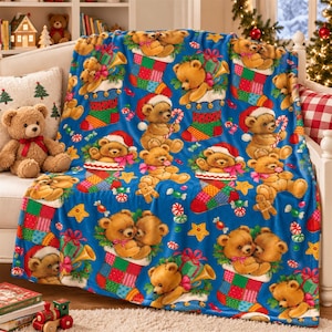 May include: A blue fleece throw blanket featuring a repeating pattern of brown teddy bears, colourful Christmas stockings, candy canes, and yellow stars. The bears are depicted wearing Santa hats or sitting inside stockings with gifts.